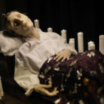 Colour photograph of a sickly wax figure and candles within the Santa Medicina sculpture