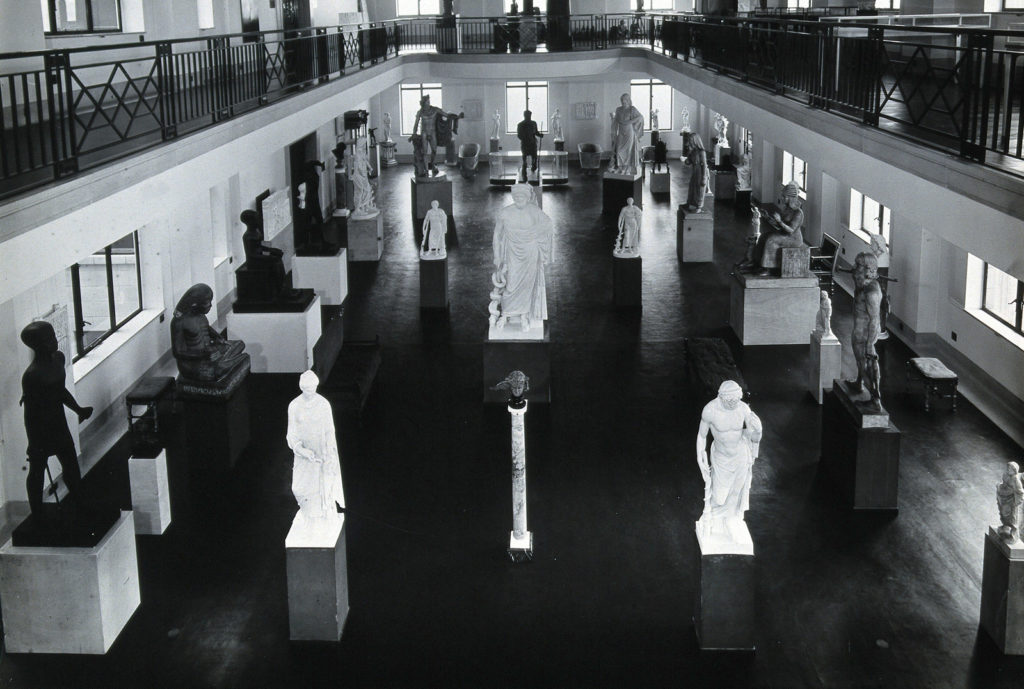 Black and white photograph of stone figure sculptures in a museum