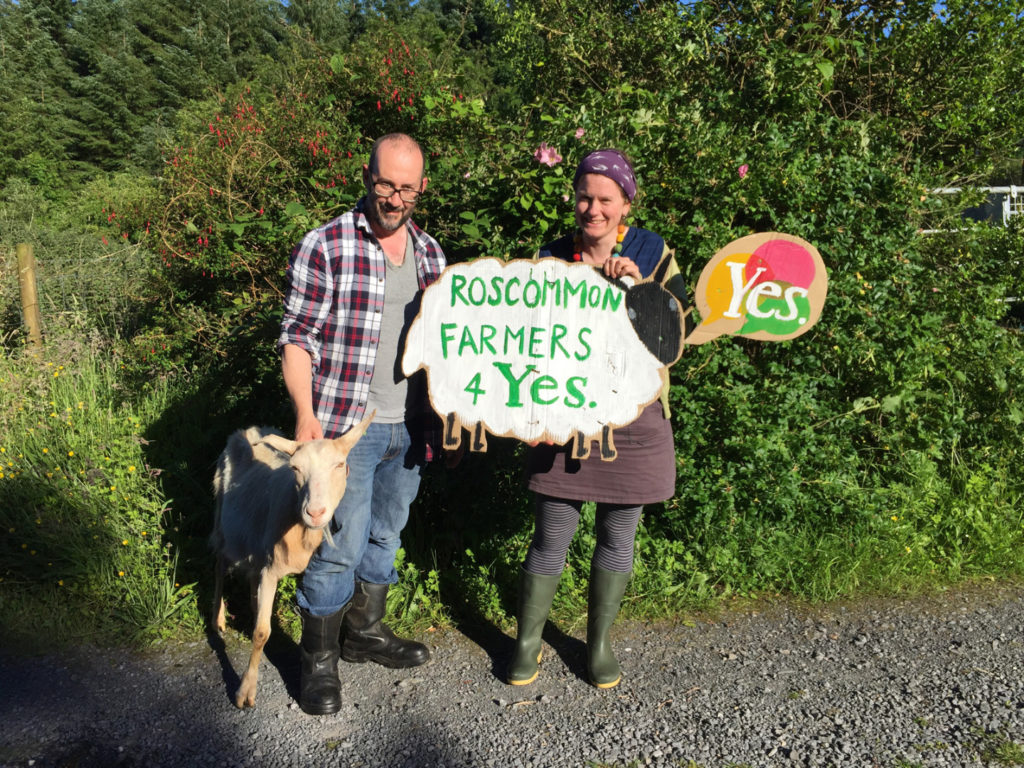 A farming couple hold a sign which reads Roscommon Farmers for Yes