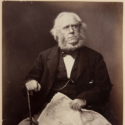 Sepia photograph of a seated James Playfair with newspaper and cane