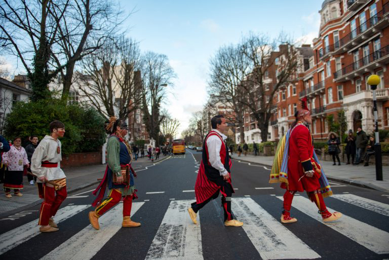 Colour photograph of traditionally dressed native Americans on a zebra crossing
