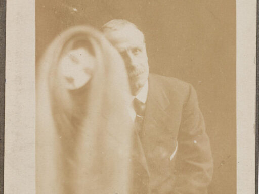 Sepia photograph of a seated man showing a spectral figure to his right