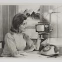 Black and white photograph of a woman holding a portable television
