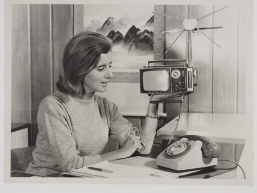 Black and white photograph of a woman holding a portable television