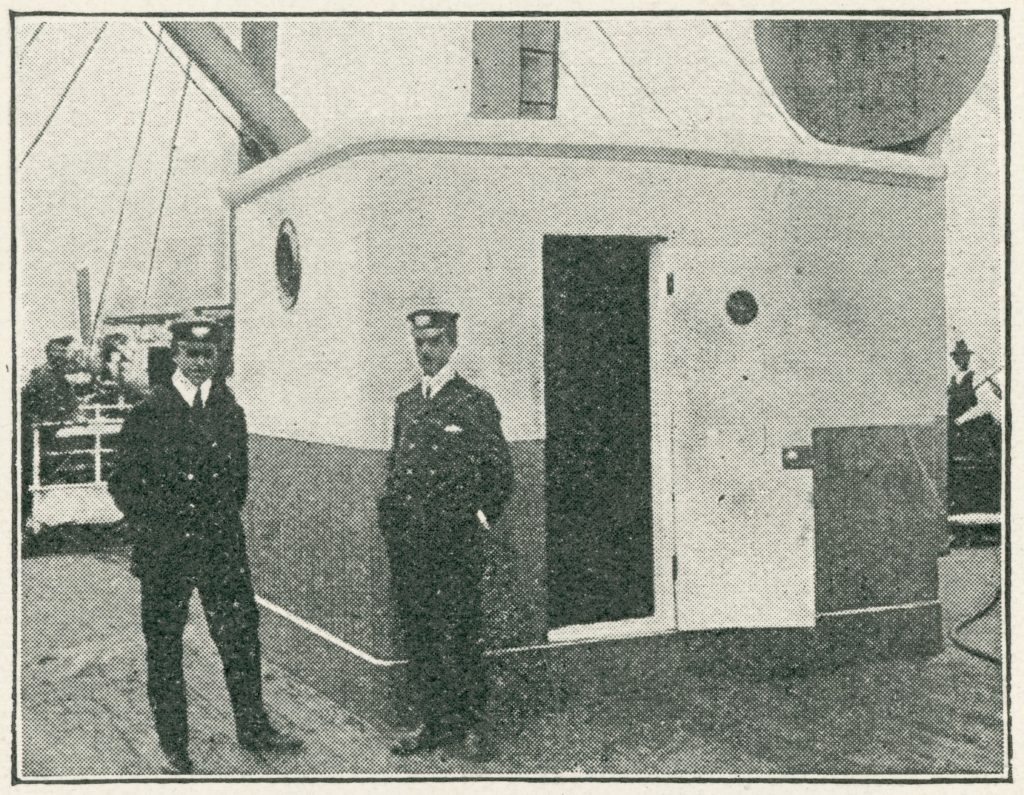 Black and white photograph of two naval staff outside a wireless station on board a ship
