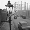 A street view with an open gas street light and the gasometers at kings cross in the distance imperial gas light and coke company gas holders greater london camden town