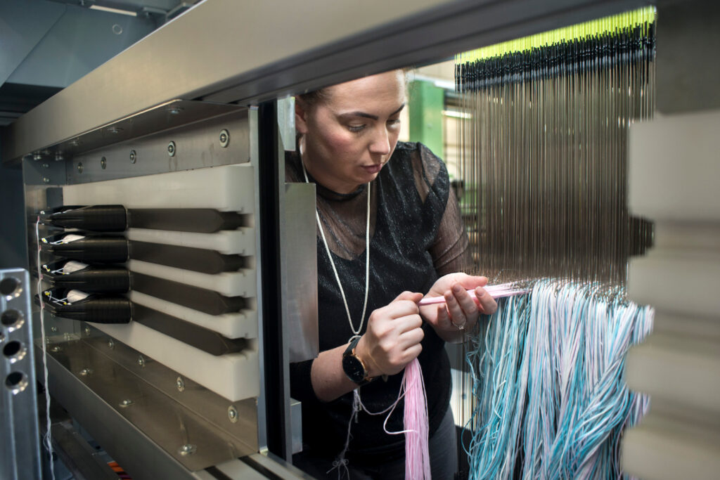 Photograph of a woman preparing a warp on a Jacquard loom