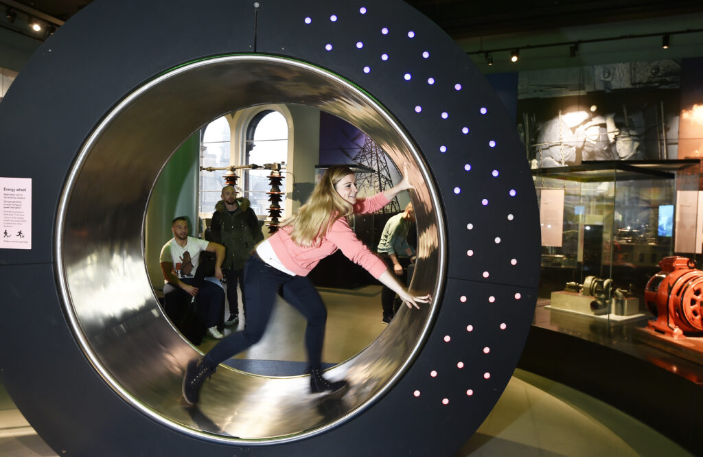 Colour photograph of girl inside an interactive spinning wheel display at the National Museum of Scotland