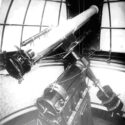 Monochrome photograph of an astrographic reflector installed within an observatory tower
