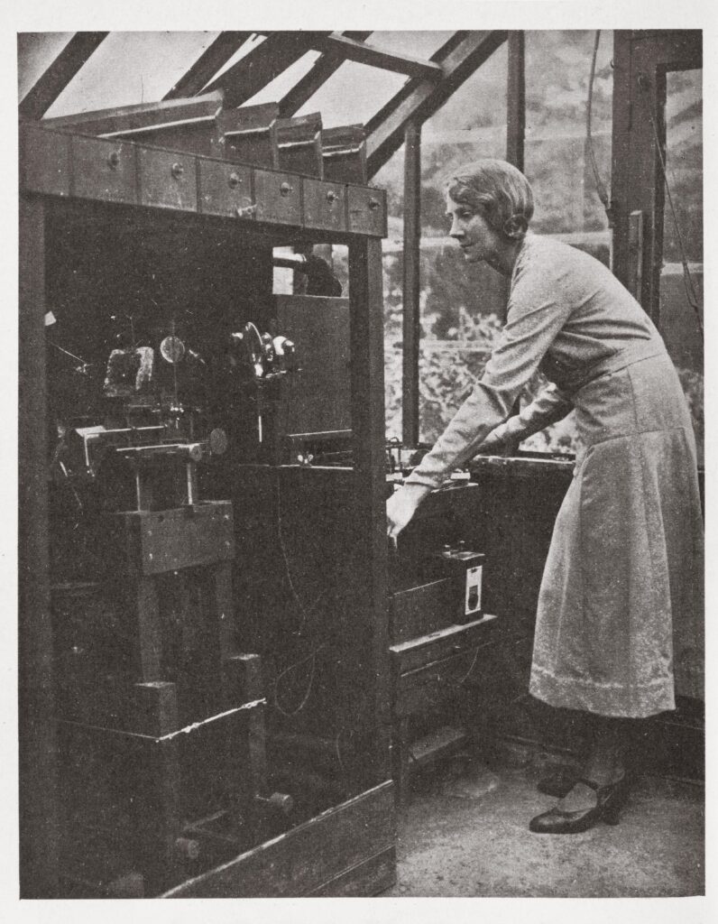 Monochrome photograph of Percy Smiths assistant Phyllis Bolté alongside one of the plant machines