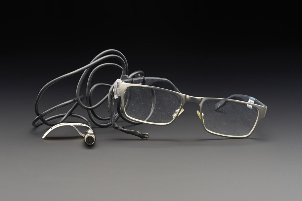 Photograph of a pair of spectacles with attached cheek movement sensor