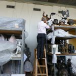 Colour photograph of Doug Millard curator at the Science Museum examining sculptures at the GTG sculpture stores