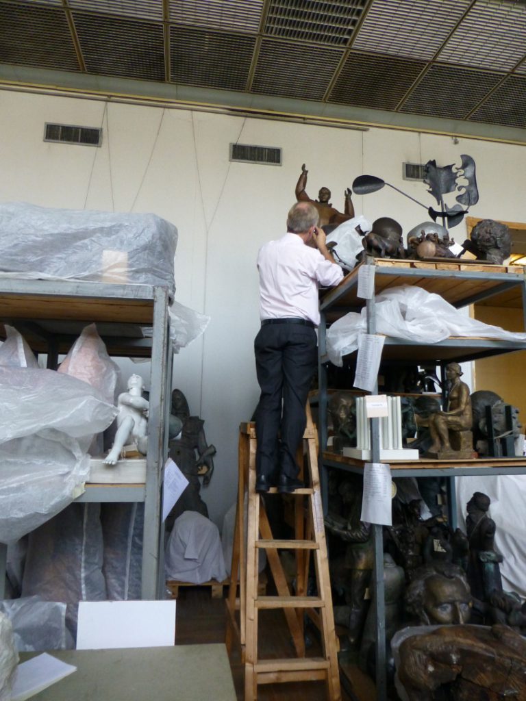Colour photograph of Doug Millard curator at the Science Museum examining sculptures at the GTG sculpture stores