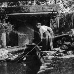 Black and white photograph of a woman working alongside a boat testing tank