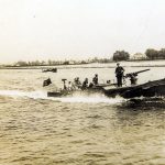 A black and white photography showing a group of people in a boat on a river