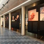 Colour photograph of a modern gallery showing large images of people afflicted with disease