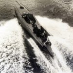 Black and white photograph of a coastal motor boat travelling at speed