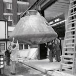 Black and white photograph of the Apollo landing craft being winched into a warehouse at the Science Museum London
