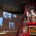 Colour photograph of a section of the Cosmonauts exhibition showing a section of a rocket with images of the rocket projected onto the wall