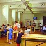 Colour photograph of museum goers using experimentation devices within a museum exhibition