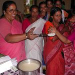 Colour photograph of an indian woman offering cooked rice to others
