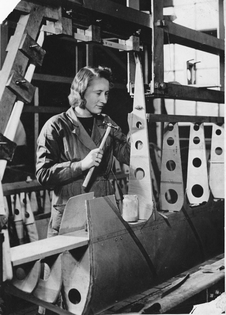 Black and white photograph of a woman working on the construction of an aircraft