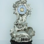 A photograph taken from the front showing the ornate silver clock