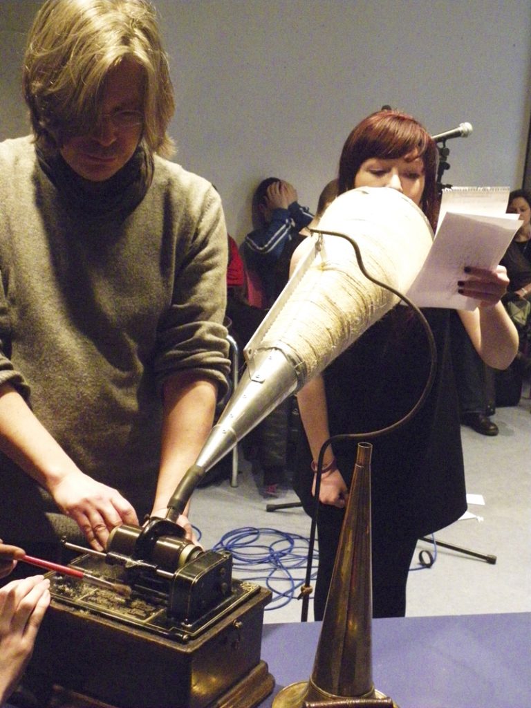 Aleks Kolkowski uses an old-looking Edison wax cylinder to record a girl's vocals