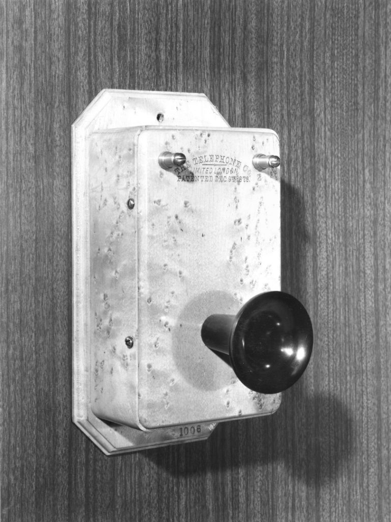 Black and white photograph of a wall mounted telephone from the late 1800s