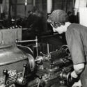 Black and white photograph of a woman working a machine tool during the mid twentieth century