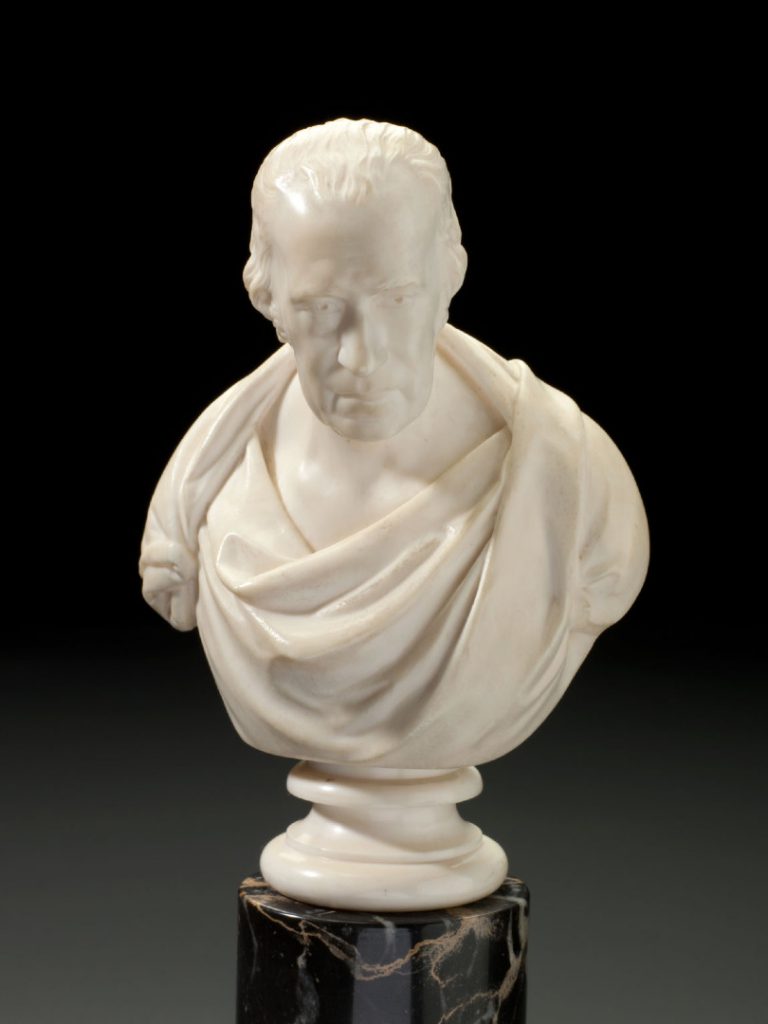 Profile view of cream marble bust of James Watt mounted on dark marble column against a graduated grey background