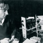 Black and white photograph of engineer Graham Wrench writing notes as he works on constructing part of the Oramics Machine