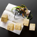 Colour photograph of a score by Graham Hearn for Hugh Davies comprising five wooden pentagons and a tape loop