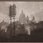 Grainy sepia photograph of a tall telegraph pylon in front of the distant silhouette of Saint Pauls Cathedral