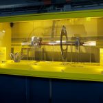 A number of components of an LHC magnet in a yellow display case