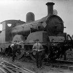 Black and white photograph of two railway engineers standing next to a steam train