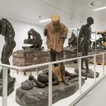 Colour photograph of a room inside a museum displaying sculptures of human forms