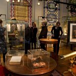 Colour photograph of a group of visitors walking through an exhibition of old scientific instruments