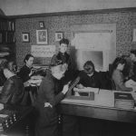 Black and white photograph from the 1880s of 8 women attempting to classify stars from recorded observations