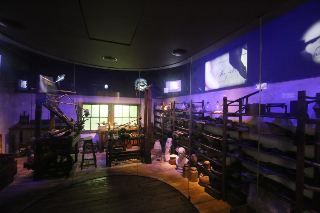 A view of the Watt's workshop exhibition showing the curved glass wall separating viewers from the workshop