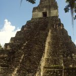 A large, ancient looking pyramidal temple with steps leading up the front to a doorway at the top
