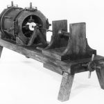 Black and white photograph of a working model of a wooden machine for boring holes in wood
