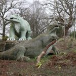 Colour photograph of two concrete Iguanadon models from the nineteenth century in different states of repair