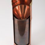 Colour photograph of a well-preserved brass rain gauge showing the funnel bottle pail and measuring cylinder