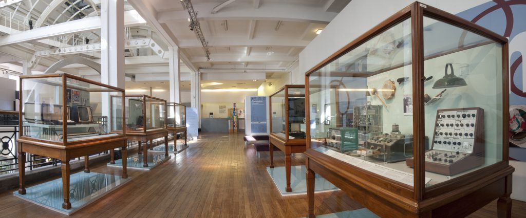 Long view of 5 display cases within the exhibition displaying a variety of electronic music items