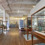 Long view of 5 display cases within the exhibition displaying a variety of electronic music items