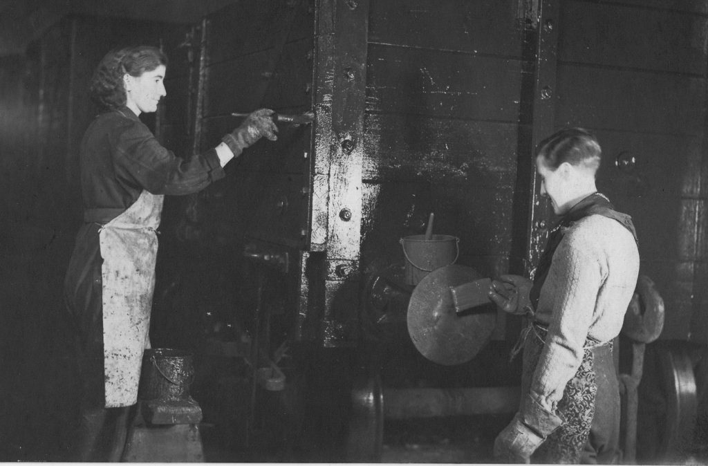 Black and white photograph of a man and a woman painting a railway carriage