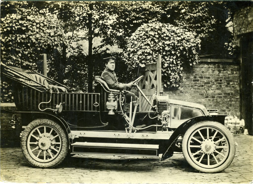 Black and white photograph of an early Renault motor car with chauffeur from the early twentieth century