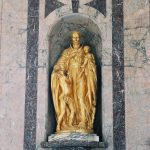 Colour photograph of a bronze sculpture depicting a Belgian male alongside two African people