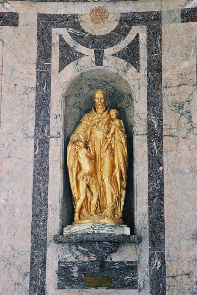 Colour photograph of a bronze sculpture depicting a Belgian male alongside two African people